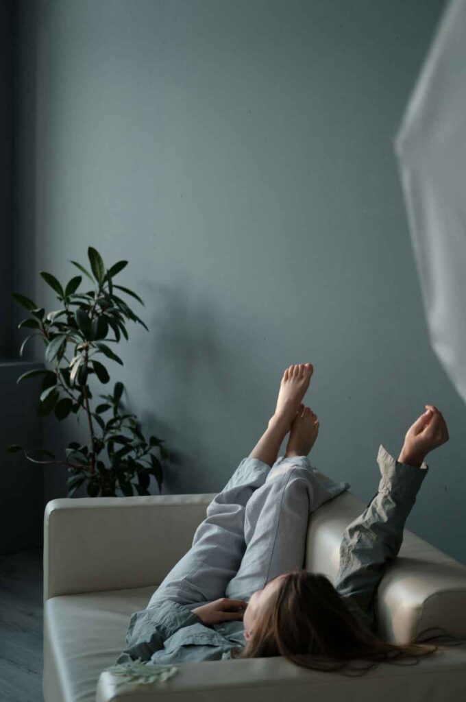 Person lying on a sofa with legs up, representing need for therapy for burnout in Janesville.