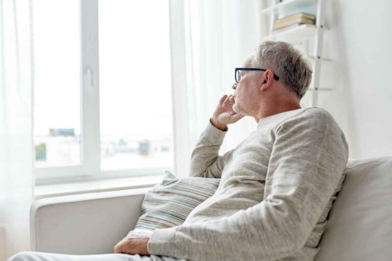 "Man gazing thoughtfully out a window, illustrating need for burnout therapy in Janesville, Wisconsin. "