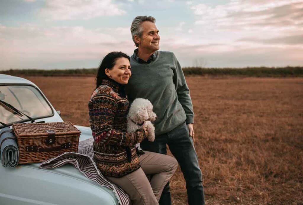 Smiling couple with dog enjoying outdoor time, showing connection built through addiction and couple counseling in janesville, wi.