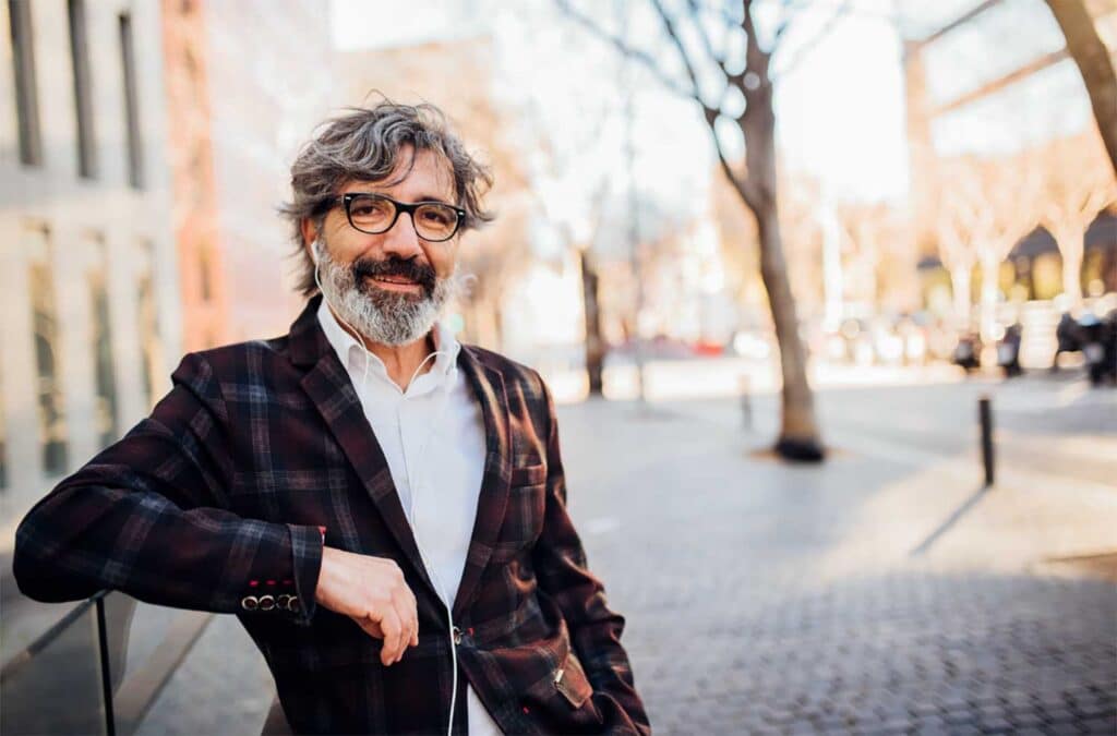 Confident man with glasses smiling outdoors, representing experienced anxiety therapists in Wisconsin.